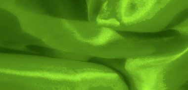 Bulanık akan yeşil kumaş pürüzsüz geçişler ve yumuşak gölgeler sergiliyor. Huzuru ve sanatsal, dokunsal kaliteyi çağrıştıran zarif kıvrımlarla ışığı yakalıyor..