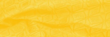 Karmaşık desenli zengin sarı kumaş bulanıklığı. Kumaş kıvrımları yumuşak ve pürüzsüz görünüyor, bu da resme derinlik katıyor. Materyalin dokusu ışıkla vurgulanır.