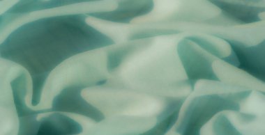 Nane yeşili kumaş zarif bir şekilde akar, yumuşak gölgelerin etkileşimini ve bu minimalist tasarımda doğal kıvrımları arttıran hassas bir şebeke deseni ile..