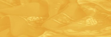 Görüntü. Zarif çiçekli ve geometrik desenli canlı sarı bir kumaş. Karmaşık detaylar sergiliyor. Zarafet ve cazibe katan ışıltılı bir dokusu var..