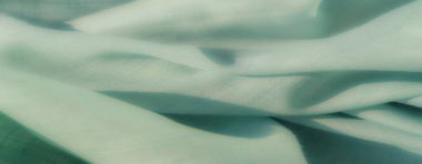 Zarif nane yeşili kumaş yumuşak kıvrımlar ve ince bir şebeke tasarımıyla zahmetsizce akar ve dağınık güneş ışığıyla vurgulanmış ince bir doku yaratır..