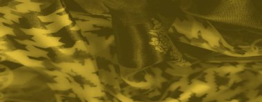 Karmaşık zincir ve houndstooth desenleri içeren sarı kumaşın bulanık yakın plan görüntüsü benzersiz bir estetik yaratıyor..