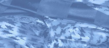 Geometrik ve zincir detaylarını içeren mavi renkli zarif tekstil tasarımı. Yumuşak kıvrımlar ve hafif ışıklandırma ona lüks ve sofistike bir görünüm verir..