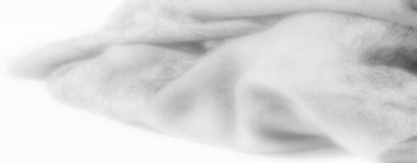 Görüntü narin beyaz kumaşın katmanlı dokusunu ortaya çıkarır, yumuşak kıvrımlar içine yumuşak gölgeler bırakır. Bu sakinleştirici tasarımın kusursuz, zarif ve dingin bir ışık kalitesi var..