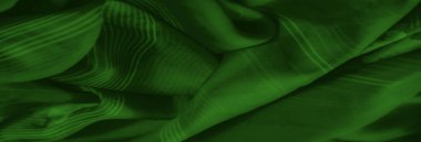 Zarif çiçek motifleri ve çizgili desenler içeren canlı yeşil kumaş bulanıklığı. Yumuşak, akışkan kıvrımlar dinamik ve görsel olarak çekici bir tekstil tasarımı yaratır..