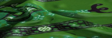 Sanatsal yeşil kumaş, dinamik soyut ve çiçek desenli, canlı siyah ve beyaz detaylar ve lüks bir dokunuş için ince dokunuşlar içeriyor..