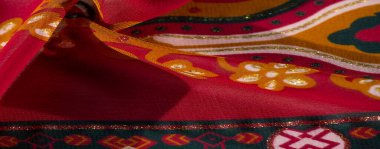 Görüntü - Bu canlı kumaş geometrik ve çiçekli kırmızı ve sarı bir palet sergiliyor, göz alıcı, dekoratif bir bitiş için ışıltılı renklerle tamamlanmış.