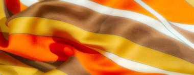 Canlı turuncu ve sarı çizgili pürüzsüz kumaş bulanıklığı, koyu kahverengi aksanlı. Akan desen ve sıcak renkler derinlik ve enerji getirir, kumaşın canlı görünümünü güçlendirir.