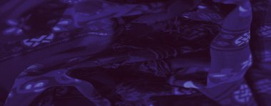 Bulanık bir görüntü, karmaşık çiçek ve soyut motiflerle mor dokuma sahip desenleri ve dokusunu vurgulamak için hafifçe aydınlatılmış. Tasarım zarafet ve derinlik yayar..