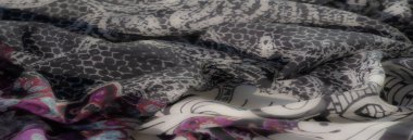 Mor, mavi ve kırmızı renkte parlak desenli bulanık kumaş. Yumuşak beyaz bir tabanda karışık girdaplar ve çiçeklerle akıyor..