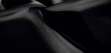 Koyu siyah kumaştan bulanık. Yumuşak kıvrımlarla örtülmüş. İnce dokular, minimalist ve zarif bir tasarım için pürüzsüz gölgeler ve ince gölgeler ortaya çıkarır..