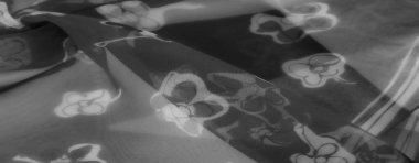 Bulanık gri kumaş, yumuşak kıvrımlı ve yarı şeffaf bir dokuya sahip çiçek deseni sergiliyor. Hassas detaylar ışık ve gölgenin etkileşimini vurgular..