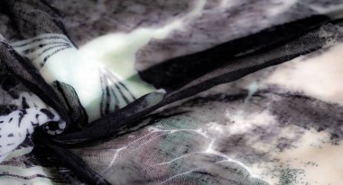 Yeşil aksanlı, katmanlı siyah beyaz kumaşın bulanık görüntüsü zarif dokusunu ve karmaşık akış düzenini vurguluyor..