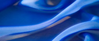 Yumuşak röfleli ve pürüzsüz desenli zengin mavi kumaşın bulanık soyut kıvrımları, sakin ve çağdaş sanatsal bir kompozisyon oluşturur..