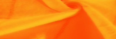 Turuncu ve sarı kumaşın bulanık görünümü pürüzsüz geçişler ve ince dokular oluşturarak dinamik ve sıcak bir soyut kompozisyon oluşturur..