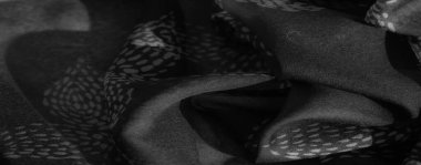 Görüntü, desenli ve pürüzsüz, akışkan kıvrımlı gri tonlu kumaş görüntüsü. Gölgeler maddenin yumuşaklığını vurgular, derinlik hissi katar..