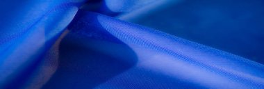 Görüntü, parlak mavi kumaşın, karmaşık kıvrımlarını ve pürüzsüz dokusunu, büyüleyici bir sanatsal etki yaratan bir ışık oyunuyla yakından görüntüler..