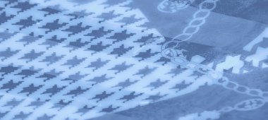 Pürüzsüz ve akan mavi kumaş zincir desenleri ve soyut şekillerle süslenmiş yumuşak dokuların ve zarif tasarımın uyumlu bir karışımını oluşturuyor..