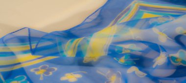 Akan mavi kumaş, zarif bir cazibe için soluk turkuaz renklerle vurgulanan, karmaşık sarı ve beyaz çiçekli ince bir çiçek deseni sergiliyor..