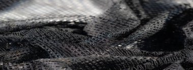 Siyah dantelli kumaşın bulanık sanatsal görüntüsü, ayrıntılı ağ benzeri desenler ve resme derinlik ve doku katan parlak noktalar sergiliyor..