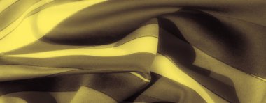 Karanlık bir zemin üzerindeki yumuşak altın dalgaların bulanıklığı katlanmış kumaş üzerinde zarif bir soyut desen oluşturur. Kibar kıvrımlar ve zengin tonlar lüks, dinamik bir görsel yaratıyor..