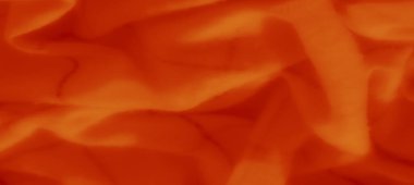 Yumuşak kıvrımlı bulanık turuncu kumaş ve zayıf çizgiler geometrik bir ızgara oluşturuyor. Doku, ışık ve gölgenin ince bir etkileşimini yaratır ve tasarıma derinlik katar..