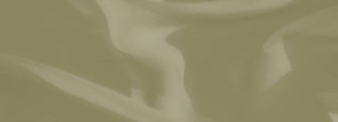 Pürüzsüz dokuları ve yumuşak ışığı olan yeşil kumaşın bulanık görüntüsü. Nazik kıvrımlar malzemede derinlik ve sanatsal desenler yaratır..