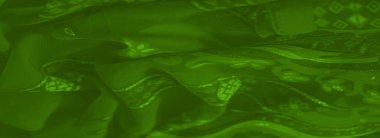 Karmaşık desenli, parlak parıltılı yeşil kumaşın bulanık görüntüsü canlı ve dokulu bir görünüm yaratıyor..