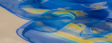 Akan mavi kumaş, zarif bir cazibe için soluk turkuaz renklerle vurgulanan, karmaşık sarı ve beyaz çiçekli ince bir çiçek deseni sergiliyor..