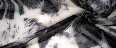 Siyah, beyaz ve yeşil tonlarda bulanık kumaş tasarımı, karmaşık desenler ve katmanlı sanatsal elementlerle akıcı, yumuşak bir doku sunar..