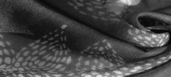 Görüntü. Gri tonlu kumaş, kumaşın hassas ve katıksız doğasını vurgulayan girdap şeklinde, yapraktan esinlenmiş bir desen içeriyor. Doku doğal kıvrımlar ve ışık kontrastı ile geliştirilir..