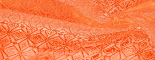 Pürüzsüz ve parlak dokusuyla bulanık turuncu kumaş. Karmaşık bir desen içeriyor. Kumaşın soyut tasarımı, sıcaklığın özünü yansıtan lüks ve görsel açıdan ilgi çekici bir sahne yaratıyor.