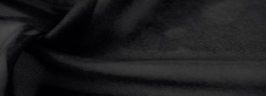 Görüntü, katlanmış siyah kumaş üzerinde ışığın ve gölgenin hassas etkileşimini ortaya çıkararak, pürüzsüz ve lüks bir sona sahip soyut ve sofistike bir doku oluşturur..