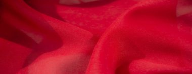 Yumuşak kırmızı kumaş kıvrımlarının bulanık detaylı görünümü, canlı renk geçişleriyle pürüzsüz bir dokuyu vurguluyor, arka plan veya tasarım kullanımı için mükemmel.