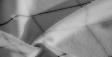 Akan kumaşın bulanık yakın çekimi gri tonda katlanır ve yumuşak siyah çizgiler modern, minimalist bir doku yaratır. Yumuşak ışık ve gölgeler kıvrımları vurgular.