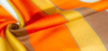 Bulanık turuncu, sarı ve kahverengi çizgili kumaş yumuşak kıvrımlı ve saten gibi pürüzsüz bir dokusu var. Renklerin ve gölgelerin etkileşimi resme derinlik ve sıcaklık ekler