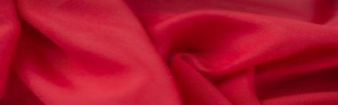 Zarif kıvrımları olan kırmızı kumaşın bulanık görüntüsü ve zengin desenli bir yüzey, tekstil, sanat veya arka plan için canlı, soyut bir estetik ideal sunuyor..