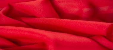 Görüntü - Yumuşak kıvrımları ve doğal kıvrımları olan parlak kırmızı bir kumaş, yaratıcı tekstil uygulamaları ve arka planlar için birinci sınıf kalitesini ve uygunluğunu vurguluyor.