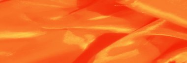 Dalgalanan dokuları olan koyu turuncu kumaş. İpeksi yüzeyde ışık ve gölgenin etkileşimi tekstil zarafetini arttırır..