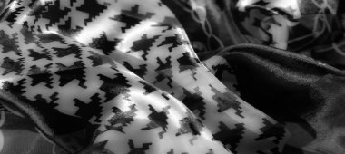 Görüntü: Çarpıcı houndstooth desenleri olan dokulu gri pullu kumaş, ayrıntılı zincir motifleriyle iç içe geçmiş, derinlik, zarafet ve modern entelektüellik katıyor..