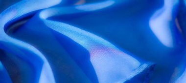 Bulanık: Yumuşak katlar ve pürüzsüz detaylarla çekilen canlı bir mavi kumaş, bu tekstil dokusunun zarafet ve sanatsal potansiyelini vurguluyor.