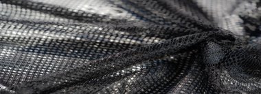 Parlak aksanlı ve karmaşık desenli karmaşık siyah örgü kumaş. Yansıtıcı ızgara benzeri doku derinlik ve zarafet ekler..