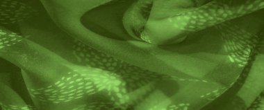 Yumuşak, dokulu desenli yeşil kumaşın bulanık görüntüsü hareket hissi yaratıyor. Işık ve gölge, kumaşın nazik kıvrımları üzerinde güzelce etkileşir..