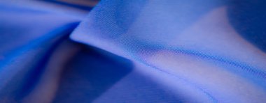 Yumuşak ışıkta çekilmiş bulanık mavi kumaş zarif kıvrımlar ve saten zerafetini vurgulayan pürüzsüz bir doku.