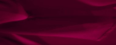 Karmaşık kıvrımları ve pürüzsüz kadife dokusuyla koyu kırmızı kumaşın bulanık görüntüsü. Akan perdeler yumuşak gölgeler ve renklerle soyut bir zemin oluşturuyor..