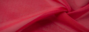 İnce kıvrımları ve karmaşık dokuları olan canlı kırmızı bir tekstil bulanıklığı, ince işçiliği ve kumaşın yüzeyinin zarafetini sergiliyor..