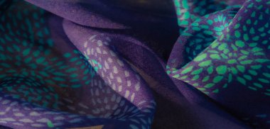 Görüntü, turkuaz renklerle güzel detaylı mor bir kumaş. Doku ve zarafeti ortaya çıkarmak için sanatsal olarak katlanmış. Renklerin ahenkli karışımı kumaşın gelişmişliğini arttırır.