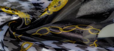 Siyah-beyaz houndstooth kumaşından bir bulanıklık ve altın zincir süslemeleri. Lüks kıvrımlar sanatsal ve karmaşık bir kompozisyon oluşturuyor..