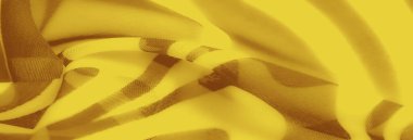 Kahverengi dalgalı desenli bulanık sarı kumaş. Bu yakın çekim, sanatsal ve dinamik bir kompozisyonda dokunun ve hareketin özünü yakalar..