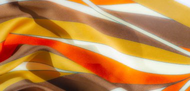 Pürüzsüz, turuncu, sarı ve kahverengi tonları olan saten benzeri kumaş üzerinde bulanık bir etki. İnce mavi çizgilerle aksanlı. Akan çizgiler katmanlı katmanlı katmanlarda rahat, sanatsal bir estetik oluşturuyor..